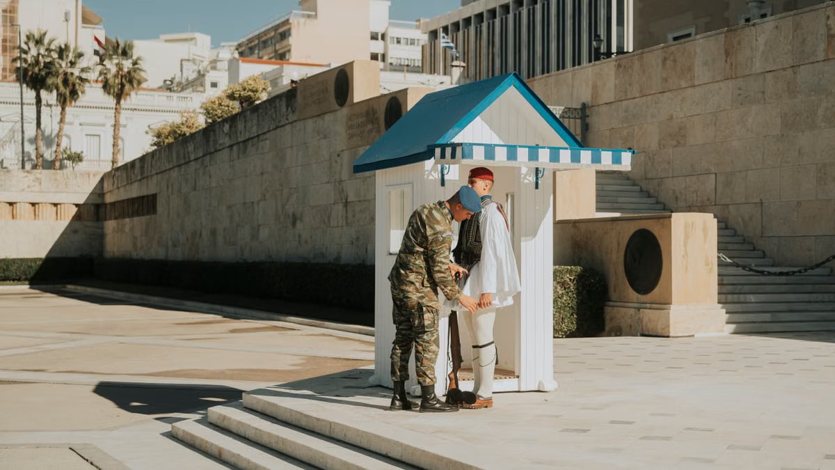 Greek Presidential Guard soldier in traditional uniform at Athens monument.